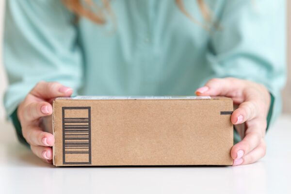 Woman holding in hands delivered goods in cardboard box. Mock-up friendly design with copy space.